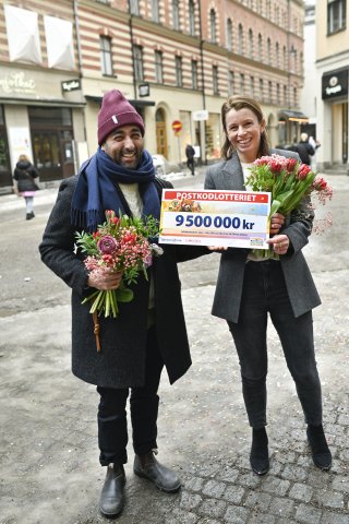 Foto på en man och en kvinna med blombuketter och checken som ler mot kameran