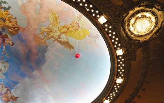 En röd ballong som svävar i Dramatens tak